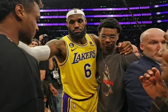 LeBron James made history on Tuesday night. In his long-awaited regular season debut on Nov. 18, the 40-year-old superstar officially became the first player in NBA history to play 23 seasons, breaking his tie with Vince Carter. And while his return energized the arena, the Los Angeles Lakers found themselves in a surprising back-and-forth battle before finally pulling away to beat the Utah Jazz 140-126. Utah came out firing, pushing the pace and dropping 71 points in the first half. The Lakers, meanwhile, were working LeBron back into the lineup after he missed training camp and the first 14 games with a sciatica issue. But Los Angeles locked in after halftime, exploding for 73 second-half points to take control. Here’s a full breakdown of LeBron James’ performance in his 2025-26 season debut. LeBron James’ Stats vs. the Jazz Points: 11 Field goals: 4-of-7 3-pointers: 2-of-3 Free throws: 1-of-4 Rebounds: 3 Assists: 12 Steals: 1 Blocks: 0 Turnovers: 1 Fouls: 0 Plus/minus: +1 Minutes: 30 LeBron returned with a classic playmaking performance — a double-double (11 points, 12 assists) — in 30 minutes on the floor. LeBron’s Emotional Return: “A Lot of Joy” LeBron was the last player to run out during introductions and the first to be announced before tip-off, drawing the loudest cheers from the sold-out crowd of 18,997 at Crypto.com Arena. And every flashy pass had fans roaring. Even though Luka Doncic stole the scoring spotlight with 37 points and 10 assists, the night still belonged to LeBron’s comeback. “It was just fun to be out there with the guys,” LeBron said. “It’s been rough mentally… I’ve never missed the beginning of a basketball season since I was nine years old.” By the time he checked out midway through the fourth quarter, he had pushed the Lakers to a 20-9 run and helped them build their biggest lead of the night. Coach JJ Redick praised his performance: “He played with the right spirit. Very unselfish. Didn’t force anything… Really good to have him back.” How LeBron Changed the Game LeBron’s return instantly boosted the Lakers’ offense: Austin Reaves scored 26 points on efficient shooting. Deandre Ayton finished with 20 points and 14 rebounds, crediting LeBron’s passes for several easy buckets. Jake LaRavia added 15 points, also benefiting from LeBron’s playmaking. “I’m sure with some of these passes he didn’t even see me cutting,” Ayton joked. “He’s making your life easy.” The Lakers ended up with their highest-scoring game of the season and shot a season-best 59.5% from the field. Reaves summed it up perfectly: “We have two of the best passers to ever touch a basketball… the game should be pretty easy.” Jazz Put Up a Fight Utah didn’t go quietly: Keyonte George: 34 points, 7 assists Lauri Markkanen: 31 points The Jazz led 36-27 after the first quarter and 71-67 at halftime. But the Lakers tightened their defense, holding Utah to just 36 points in the next 18 minutes, completely flipping the momentum. Milestones for LeBron Even with a modest scoring night, LeBron reached two major marks: His two early 3-pointers moved him past Reggie Miller to 6th all-time in NBA 3-pointers made. His third-quarter layup extended his record streak of double-digit scoring games to 1,293, a run that started in January 2007. What’s Next for the Lakers? After the win, the Lakers move to 11-4 on the season and now get a short break. Their next game? A rematch with the Jazz on Sunday in Salt Lake City. LeBron says the rhythm will come: “My wind was a little shaky… but everything tonight was as expected. I was happy I was able to keep up with the guys.” If Tuesday was any indication, LeBron’s 23rd season might still have plenty of magic left.